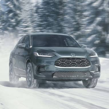 2027 Honda HR-V EX-L in Nordic Forest Pearl front view driving on a snowy road (Subcompact Crossover SUV).