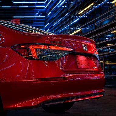 2027 Honda Civic Sedan Sport Touring Hybrid in Rallye Red rear three-quarter view showing taillight (Compact Sedan)